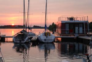 un grupo de barcos atracados en un muelle al atardecer en Hausboot FJORDBLIK en Kollund Østerskov