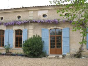 una casa con persianas azules y una puerta en Chambres d'hôtes Le Chardon Fleuri, en Teuillac