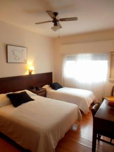 um quarto de hotel com 2 camas e uma ventoinha de tecto em Hotel San Martin em Punta del Este
