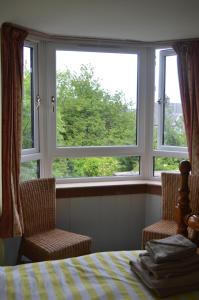 a bedroom with two chairs and a bed and two windows at Holiday Apartment Dunfermline in Dunfermline