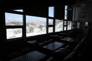 a room with couches and windows with snowy mountains at Sundeck Hotel in Perisher Valley