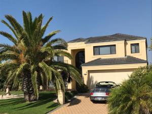 a car parked in front of a house with a palm tree at Le Boulevard in Mindarie