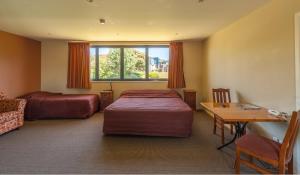 a room with two beds and a desk and a table at Waterfront motel in Blenheim