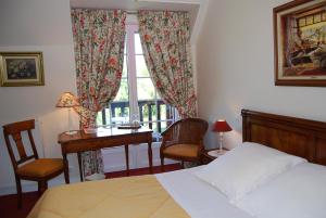 a bedroom with a bed and a desk and a window at Hostellerie de la Motte jean in Saint-Coulomb