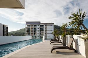 a row of chairs on a boardwalk next to a pool at Central Holborn Apartments in Townsville