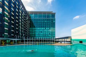 a person swimming in a pool in front of a building at The Stanley Hotel & Suites in Port Moresby