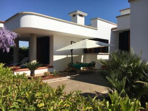 Casa blanca con patio con sombrilla en Villa Carmen, en Castrignano del Capo
