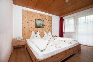 - une chambre avec un grand lit et une tête de lit en bois dans l'établissement Hotel Messnerwirt, à Anterselva di Mezzo