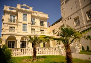 a large white building with palm trees in front of it at Hotel Vila Imperial in Elbasan