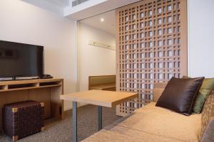 a living room filled with furniture and a tv at HOTEL MYSTAYS PREMIER Omori in Tokyo