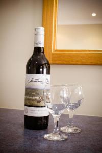 Dirranbandi Motor Inn في Dirranbandi: زجاجة من النبيذ وكأسين من النبيذ على الطاولة