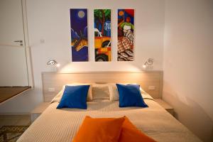 Apartment 81 في موستا: غرفة نوم مع سرير مع الوسائد الزرقاء والبرتقالية