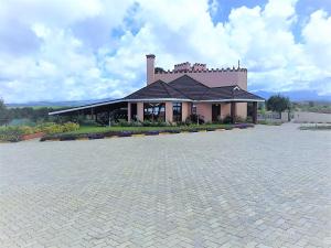 un edificio con un aparcamiento de ladrillos delante de él en Regency Mount Kenya Hotel, en Timau