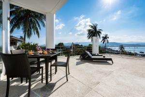 a table and chairs on a patio with a view of the ocean at Sunset Sea View Apartment in Bang Rak Beach