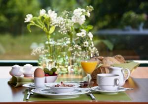 a table with a plate of food and a glass of orange juice at Nationalparkhotel Kranichrast in Schwarzenhof +16 photos
