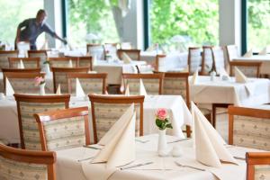 una sala da pranzo con tavoli e sedie bianchi e fiori in vasi di Nationalparkhotel Kranichrast a Schwarzenhof