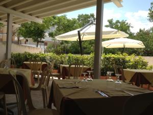 restauracja ze stołami i parasolami na patio w obiekcie Hotel Turismo w mieście Metaponto