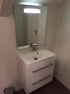 ein weißes Badezimmer mit einem Waschbecken und einem Spiegel in der Unterkunft Bed & Breakfast Klokgaaf in De Koog
