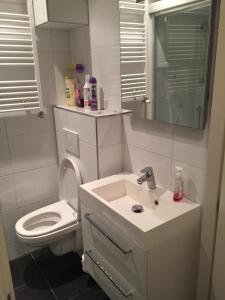 a white bathroom with a sink and a toilet at Bed & Breakfast Klokgaaf in De Koog