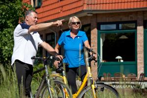 a man and a woman standing next to their bikes at Nationalparkhotel Kranichrast in Schwarzenhof