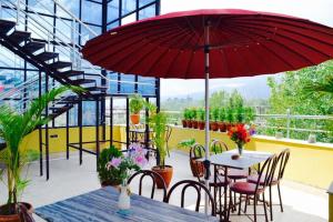 a patio with a table with a red umbrella at Hotel Regal Airport in Kathmandu