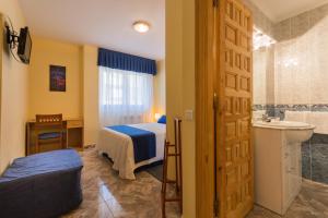 a bedroom with a bed and a bathroom with a sink at Apartamentos La Bolera in Isla