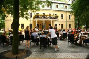 a group of people sitting at tables in front of a building at Palac w Rybnej in Rybna