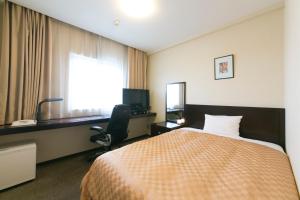 a hotel room with a bed and a desk and a window at Hotel nanvan Yaizu in Yaizu