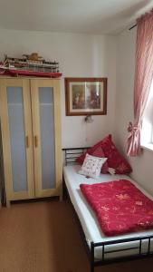 ein Schlafzimmer mit einem Bett mit einer roten Decke darauf in der Unterkunft Gästehaus Alwine Wohnung 6 in Grömitz