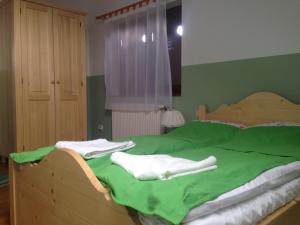 a bed with green sheets and white towels on it at Eszter Guesthouse in Sîncrăieni