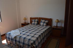 a bedroom with a bed with a blue and white plaid blanket at Alojamentos dos Mangues in São Martinho do Porto