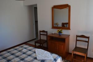 a bedroom with a bed and a mirror and two chairs at Alojamentos dos Mangues in São Martinho do Porto