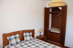 a bedroom with a bed with a mirror and a lamp at Alojamentos dos Mangues in São Martinho do Porto