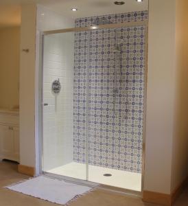 a glass shower with a blue and white tile wall at Cragend Grange in Rothbury
