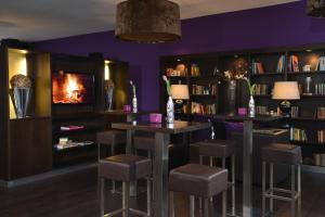 a library with two bar stools and a fireplace at Hotel Friends in Cologne