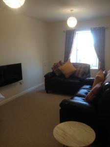 a living room with a couch and a tv at Acorn Apartment in Dufftown