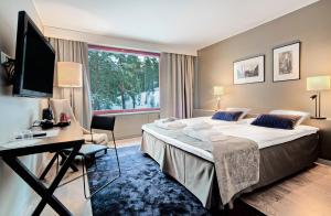 a hotel room with a large bed and a desk at Hotel Korpilampi in Espoo