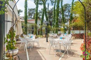 un patio con mesas blancas, sillas y árboles en AluaSun Marbella Park, en Marbella