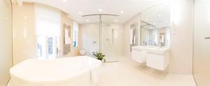 Baño blanco con bañera blanca grande y lavabo en Residence Glamour Excellent, en Praga