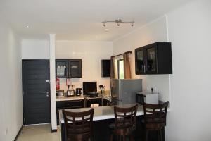 a kitchen with black cabinets and a table with chairs at Surfers Cove Apartments in Bel Ombre