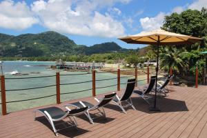 a deck with chairs and a table and an umbrella at Surfers Cove Apartments in Bel Ombre