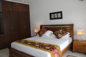 a bedroom with a large bed with two lamps and two cabinets at Surfers Cove Apartments in Bel Ombre
