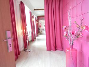 un corridoio con tende rosa e un vaso con fiori di Lush Apartment in Ensival with sauna a Ensival