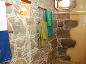 a bathroom with green towels hanging on a stone wall at Casa Rural La Pileta - Bentejui in Agüimes