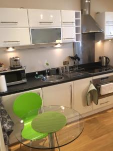 cocina con mesa de cristal y silla verde en Number 10 Serviced Apartment - City Center en Southampton