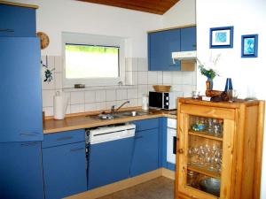 a kitchen with blue cabinets and a sink and a window at Bungalow im Feriendorf Uslar mit Gartenterrasse in Uslar