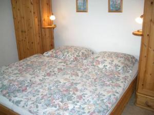 a bed with a floral comforter and two pillows at Bungalow im Feriendorf Uslar mit Gartenterrasse in Uslar