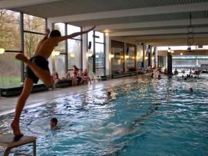 a boy jumping in a swimming pool at Bungalow im Feriendorf Uslar mit Gartenterrasse in Uslar +31 photos