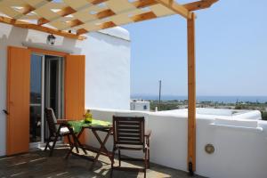 patio ze stołem i krzesłami na balkonie w obiekcie Aigaio Studios tinos w mieście Tinos