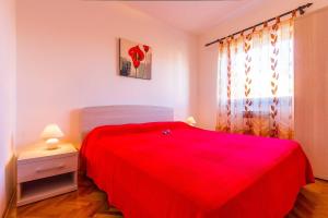 a bedroom with a red bed and a window at Apartments Valbandon in Fažana